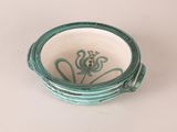a green and white bowl sitting on top of a white table