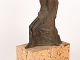 bronze statue of a woman sitting on a block on a white background