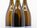 trois bouteilles de vin posées les unes à côté des autres sur une surface blanche