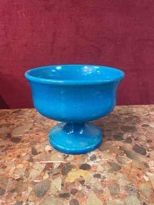 un bol bleu posé sur une table, avec un mur rouge en arrière-plan