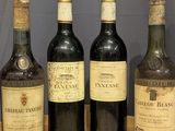 four bottles of wine are lined up on a wooden table