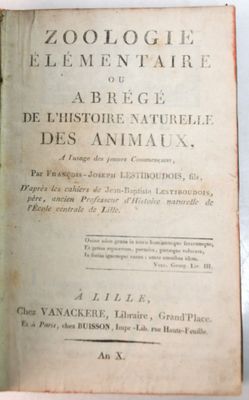 un vieux livre posé sur une table, à côté d'une plante