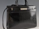 sac à main en cuir noir avec des finitions argentées sur fond gris