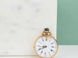 an antique pocket watch sitting on a marble block next to a pair of scissors