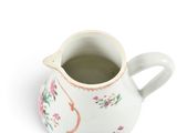 a white pitcher with pink flowers on it on a white surface
