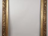 a gold framed mirror with a floral design on the edge
