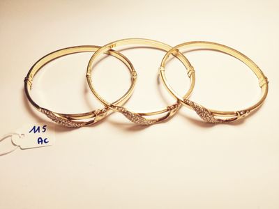 three gold bang bracelets with diamonds on a white background