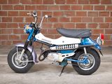 a small blue and white motorcycle parked in front of a brick wall