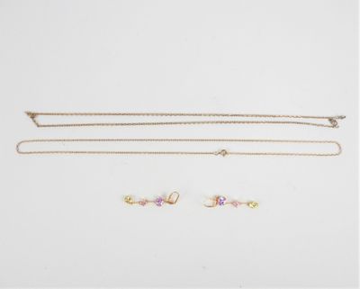 trois colliers en or et une paire de boucles d'oreilles sur fond blanc
