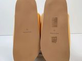 the soles of a pair of yellow shoes on a white surface