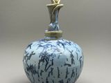 un vase bleu et blanc surmonté d'une statuette