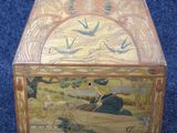 a wooden box with a painting on it on a blue carpet