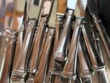 a lot of silverware on a table with a calculator in the background