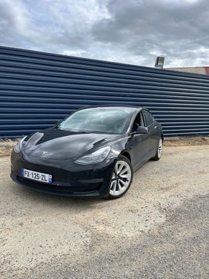 une Tesla Model S noire garée devant un mur bleu