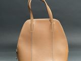 a tan handbag sitting on top of a gray surface