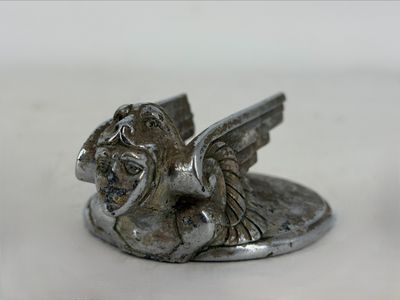 a silver statue of a winged animal on a white surface