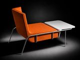 une chaise orange et une table blanche dans une pièce sombre