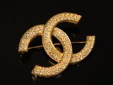 un gros plan d'une broche en or sertie de diamants sur un fond noir