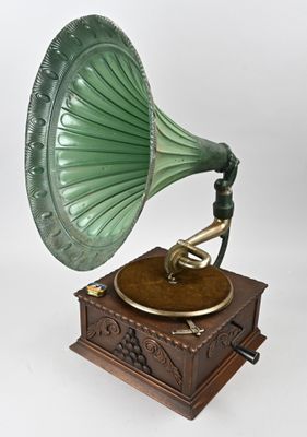un vieux gramophone vert posé sur un socle en bois, sur fond blanc