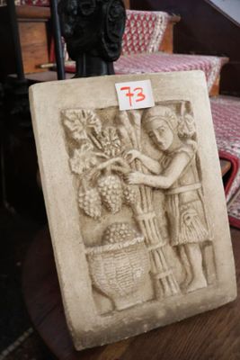 une statue représentant une femme tenant un panier de raisins posé sur une table