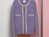 un cardigan violet suspendu à un cintre devant un mur rose