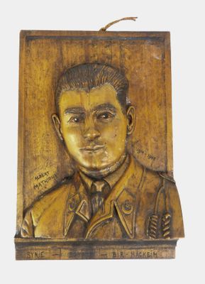 une photo d'une plaque en bois sur laquelle figure le portrait d'un homme