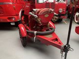 a red fire truck with a hose attached to it ' s side