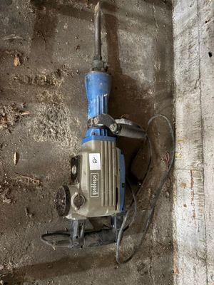 une perceuse accrochée au mur à côté d'un morceau de béton