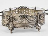 une assiette en argent ancienne avec des poignées et des poignées sur un support