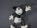 figurine de mickey mouse sur une surface grise avec un fond gris