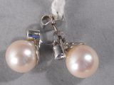 pair of white pearl earrings with blue stones on a gray surface