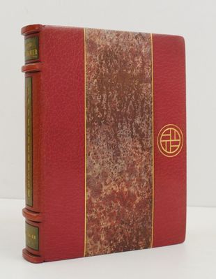 an old book with a red cover and gold trim