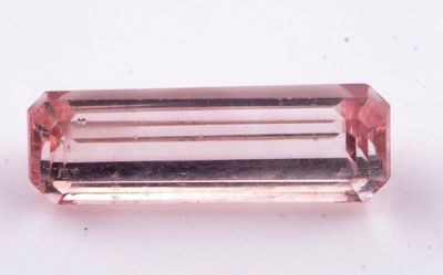 un gros plan d'une tourmaline rose posée sur une surface blanche