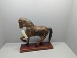 statue of a horse with a book in its mouth on a white surface