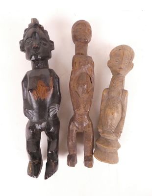 trois figurines en bois assises les unes à côté des autres sur une surface blanche