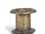 a small brass hat on a stand on a white surface