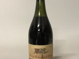 une vieille bouteille de vin posée sur une table blanche