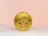 gold coin sitting on a marble surface against a pink background