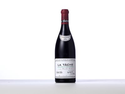 a bottle of red wine sitting on top of a white table
