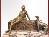 une statue représentant une femme assise sur un banc à côté d'un chien
