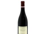 a bottle of red wine sitting on top of a white table