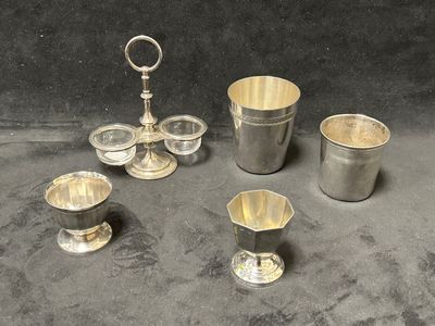 quatre tasses en argent et une cuillère en argent posées sur une table