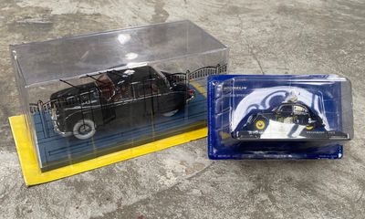 une petite voiture noire dans une boîte transparente posée par terre