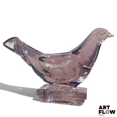 un oiseau en verre posé sur un morceau de bois