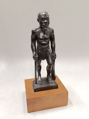 bronze statue of a man with a cane standing on a wooden base