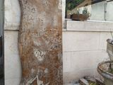 a large piece of rust on the side of a building next to a potted plant