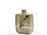 un petit vase avec un oiseau sur une surface blanche