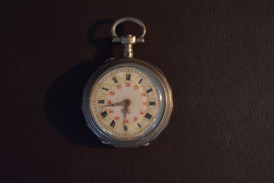 une montre de poche en argent avec un cadran blanc sur fond noir