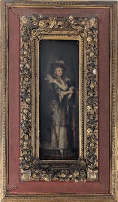 une vieille photo d'une femme portant un chapeau et une robe, dans un cadre doré