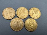 five gold sovereigns, one of which has a crown on top of it